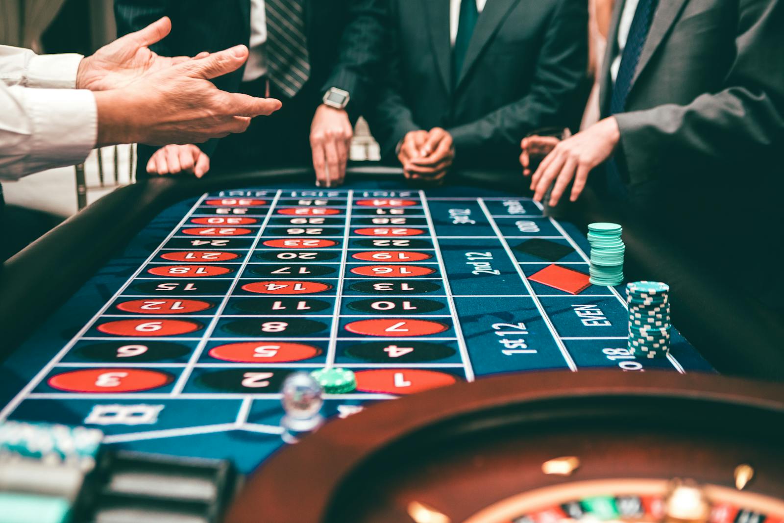 Group of people playing roulette, placing bets in a casino setting.