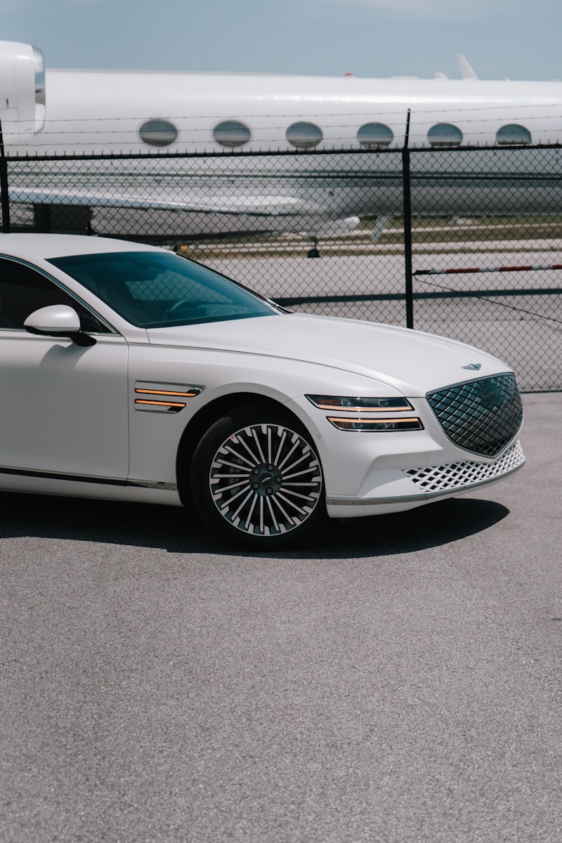 a white car parked in front of a fence