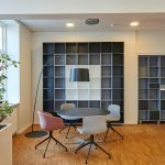 Bright and stylish office space with contemporary furniture and open shelving.