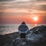 round silver-colored watch on rack during sunset