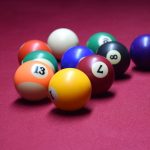 billiard balls lined up in a row on a pink surface